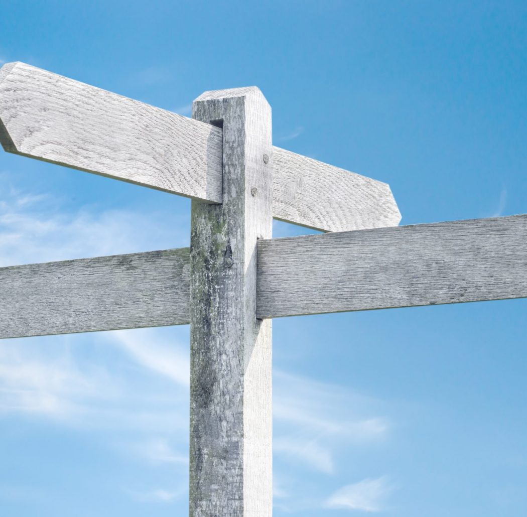 Old,Weathered,Wooden,Signpost,Against,Blue,Sky,With,Four,Sign